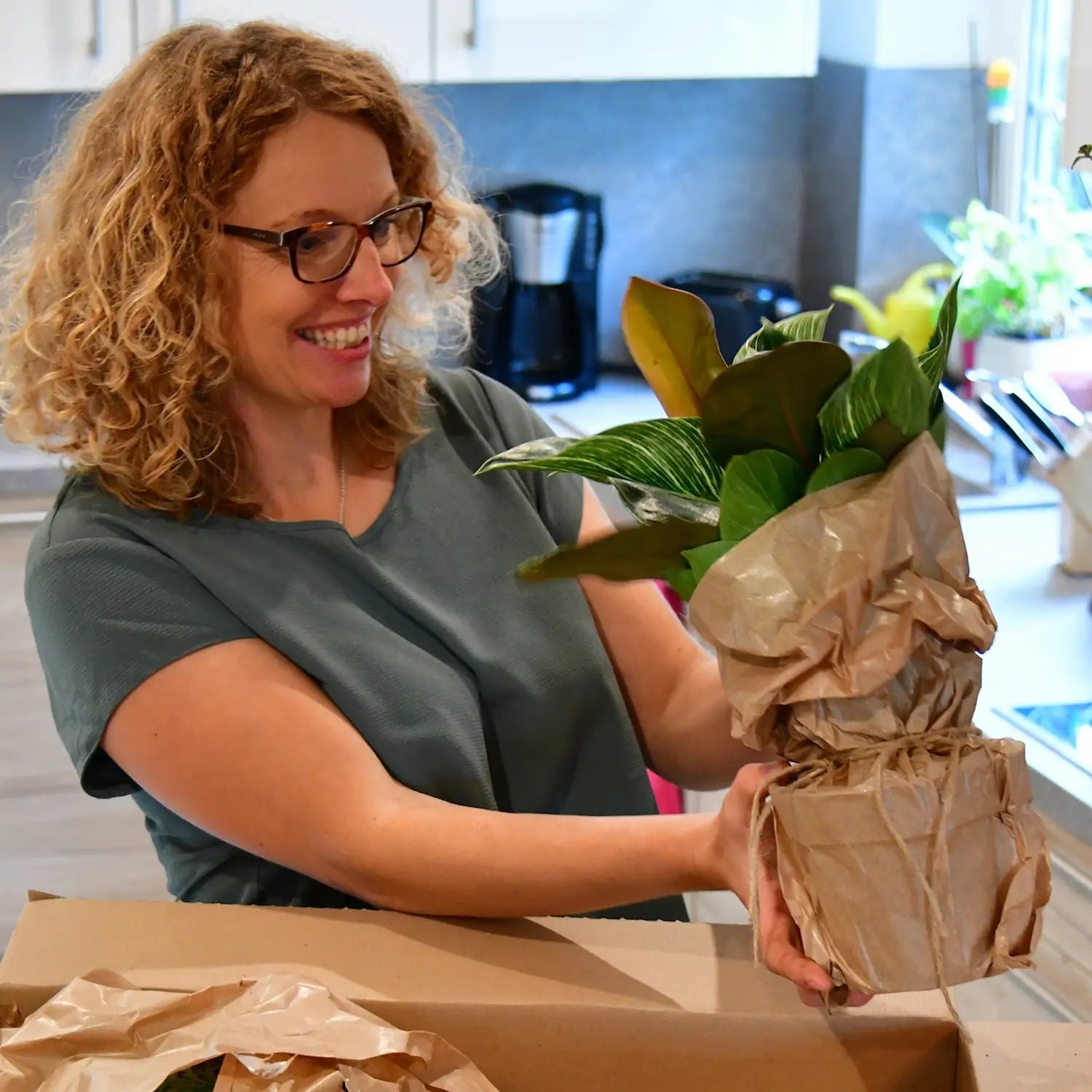 Frau öffnet Paket und freut sich über frische Pflanzen