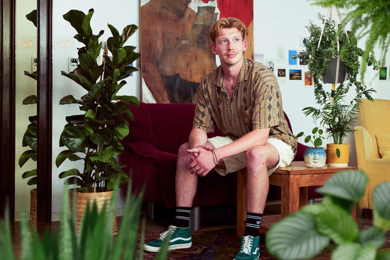 Junger Mann sitzt zwischen frischen Pflanzen die zu ihm passen